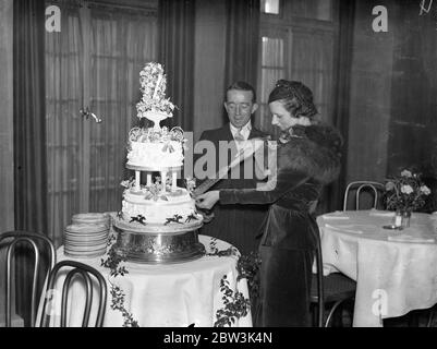 Samuel Wragg und seine Braut schneiden den Kuchen bei der Hochzeitsfeier. Samuel Wragg heiratet Miss Millicent Maud Smith im Caxton Hall-Registerbüro in London. Braut und Bräutigam schneiden den Kuchen . 27. November 1935 Stockfoto