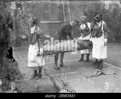 Anti-Gas-Kader geben Anzeige im East End von London. Eine Demonstration der erste Hilfe im Falle von Luftgasangriffen , organisiert von der St. John ' s Ambulance Brigade , fand in der Commercial Street , im East End von London . Hohe Beamte des Kriegsbüros schauten sich die Demonstration an. Foto zeigt, Gas maskierte Krankenschwestern tragen einen Bahre Fall. 28. September 1935 Stockfoto