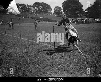 Nehmen Es In Ihrem Stride ! Musikstühle, Ballon platzen, Relais und Kartoffelrennen, mit allen Konkurrenten auf dem Pferderücken, waren ein Merkmal der montierten Gymkhana der Summer Show der Haywards Heath Horticultural Society in Victoria Park, Haywards Heath, Sussex. Foto zeigt: Miss Peggy Alle, reiten ihr Pony Wildfire, ordentlich schaufeln eine Kartoffel aus dem Scheiterhaufen während der Kartoffel-Rennen. Juli 1936 Stockfoto