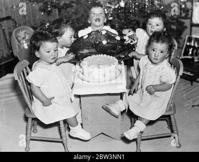 Exklusive Bilder der Dionne Quintuplets Weihnachtsfeier. Mit einem riesigen truthahn und einem ebenso großen Kuchen konfrontiert, wussten die Quins nicht, wo sie anfangen sollten. Emelie, jedoch, immer die vorderste der Babys, scheint durch den Vogel versucht. 23 Dezember 1935 Stockfoto