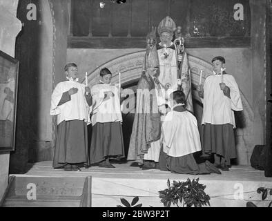 Boy Bischof thront in der ersten öffentlichen Zeremonie seit der Reformation in Guilford . Fred Brazier, im Alter von 12 als "Boy Bishop" von St. Mary of the Angels Song School, Highgate, wurde von der Rev Desmond Morse Boykott als St. Nicholas inthronisiert, in Compton Kirche, Guilford, Surrey, In der ersten öffentlichen Zeremonie seit der Reformation . Foto zeigt, der Kaplan küssen den Jungen Bischof als St. Nikolaus segnete sie während der Zeremonie. Dezember 1935 Stockfoto