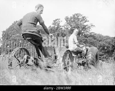 Sir Malcolm Campbell nimmt Traktor fahren. Sir Malcolm Campbell , der schneller an Land gefahren ist als jeder andere in der Welt ., fährt jetzt einen Traktor , eine der langsamsten Methoden der Fortbewegung und gefällt die Veränderung ! . Sir Malcoml ist mit dem Traktor, um das Gras für die neuen Erweiterungen zu seinem Golfplatz zu Hause schneiden, Headley Grove, Surrey. Foto zeigt, Sir Malcolm Campbell pilotieren den Traktor über das Gras in Headley Grove, Surrey. 11 Juli 1936 Stockfoto