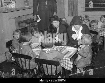 Lady Astor eröffnet erste Kinderschule in Camberwell. Die erste Kindergarten in Camberwell, in der Stafford Street Siedlung, Peckham, die von der Union of Girls Schools betrieben wird, wurde von Lady Astor eröffnet. Foto zeigt, Lady May Abel Smith mit Lady Astor, MP (rechts) unter Tee mit den Kindern in der Kindergarten Schule. 10 Dezember 1935 Stockfoto