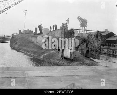 König Albert, einmal Stolz der deutschen Marine, wird in Rosyth gebrochen. Die Arbeit hat in Rosyth Dockyard, Schottland, auf die Auflösung der 20, 000 Tonnen Ex-deutschen Schlachtschiff König Albert, die von Scapa Fluss gerettet wurde, wo sie mit anderen deutschen Schiffen nach dem Krieg versenkt wurde begonnen. Der Hulk, der auf dem Kopf liegt, wird nach oben geschorben, damit das Wasser aus dem Dock herauslaufen kann. Foto zeigt, Arbeiter unter den massiven Propeller des König Albert beschäftigt, wie sie die Ausrüstung demontieren. 25 Mai 1936 Stockfoto