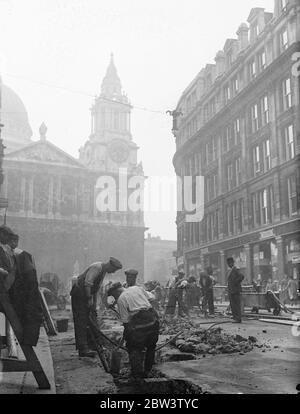 Straßenreparaturen Im Schatten Von St. Pauls ' s One - Way Verkehr Auf Ludgate Hill . Der One - Way Verkehr ist jetzt auf Ludgate Hill in Kraft, weil umfangreiche Straßenreparaturen, die gerade begonnen haben. Foto zeigt : Straße - Mender bei der Arbeit im Schatten von St . Paul ' s Kathedrale . 22 Juni 1936 Stockfoto