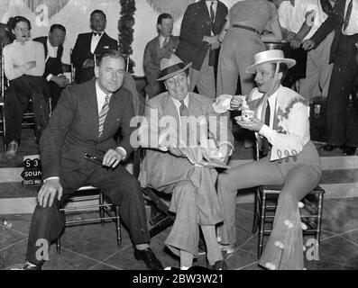 Jack Buchanan Und Elsie Randolph Pfeifen Zusammen Nach Drei Jahren Apart. Zum ersten Mal seit drei Jahren sind Jack Buchanan und Elsie Randolph Partner in einem Film. Sie erscheinen zusammen in This' ll make you whistle, das Herbert Wilcox bei Elstree macht. Das letzte Mal, dass Buchanan unter Wilcox arbeitete, war vor fünf Jahren in Good Night Vienna. Foto zeigt: Jack Buchanan (Mitte) und Herbert Wilcox warten darauf, dass Elsie Randolph eine Tasse Tee am Set in Elstree quaff. Sie ist für die Szene der falsche Rumba gekleidet 25 Jul 1936 Stockfoto