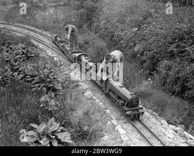 Miniaturen Eisenbahnsystem in EINEM Kenton Garten gebaut. Hobby bringt Fonds für lokale Krankenhäuser drückt Specials , und Frachter brüllen durch Stecklinge , Kreuzungen , Tunnel , über Brücken und ziehen in termini auf Zeit - alle normalen Arbeiten einer großen Eisenbahn - werden im Raum eines Gartens an Kenton , Middlesex durchgeführt . Herr . J . R . Jeffress von Kenton Grange hat eine der ehrgeizigsten Miniatureisenbahnen auf dem Gelände seines Hauses gebaut. Er entwarf sein eigenes Layout - und baute seine eigenen Lokomotiven, die einen George the Fifth. Gebaut auf 0 Gauge hat das System Stockfoto