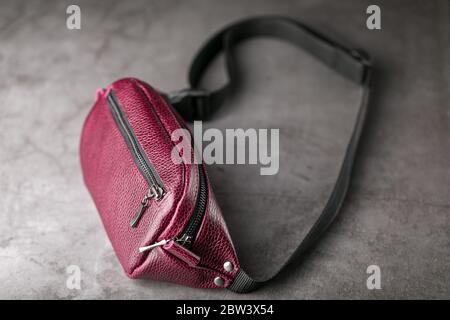 Hüfttasche aus dunkelrotem Leder, Banane auf grauem Hintergrund. Stockfoto