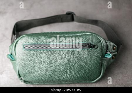 Gürteltasche aus dunkelgrünem Strukturleder, Banane auf grauem Hintergrund. Stockfoto