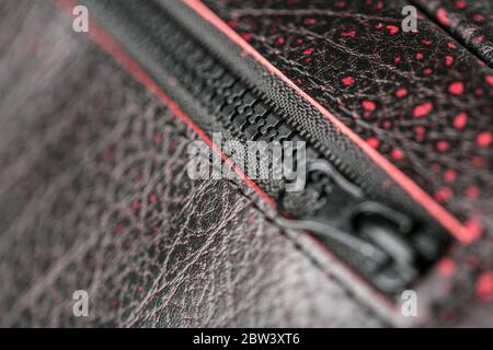 Reißverschluss-Slider für eine Tasche aus strukturiertem rotem Leder. Stockfoto