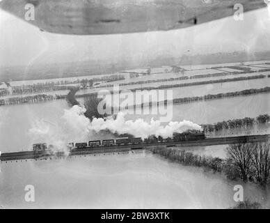 Bilder aus der Luft. Hunderte von Quadratmeilen durch Überschwemmungen von berstenden Flüssen in den Fens bedroht. Die schwerste Überschwemmungssituation seit Jahren ist die Fens , wo Tausende von Hektar Ackerland wurden von Flüssen überschwemmt, die ihre Ufer unter dem Druck von schweren Regenfällen und Frühjahrszeiten platzen . Zweihundertfünfzig Quadratmeilen Land sind von den Überschwemmungen bedroht. Foto zeigt, ein Zug über das überflutete Fenland in der Nähe von St Ives. 16 März 1937 Stockfoto