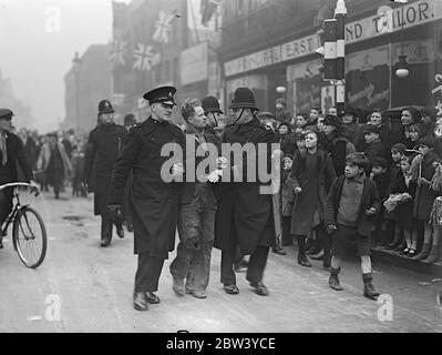 Polizei verhaften Mann als König und Königin angekommen im Volkspalast. Als der König und die Königin am neuen Gebäude ankamen, verhaftete die Polizei einen Mann in der Mile End Road vor dem Volkspalast. Der König und die Königin nahmen an der ersten öffentlichen Verlobung zusammen seit dem Aufstieg Teil. Foto zeigt, marschiert die Polizei weg der verhaftete Mann aus dem Volk ' s Palast. 13 Februar 1937 Stockfoto