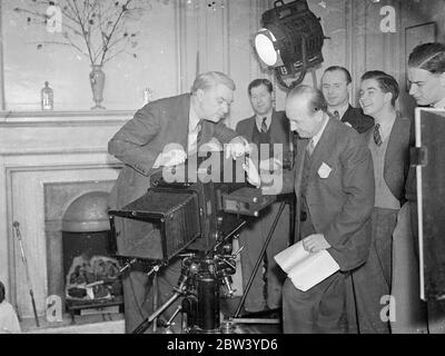 John Drinkwater verwandelt sein Londoner Zuhause in ein Studio für den Krönungsfilm. Umgekehrt wurde ein Filmstudio in das Londoner Heim eines Autors verlegt. Das Erdgeschoss von John Drinkwater's Haus in Maida Vale wird für die Filmproduktion genutzt, ist ein eigenes Szenario von Warner Brothers' Krönungsfilm das Volk des Königs. Herr Drinkwater und seine Frau und Tochter Penny, wohnen oben. In der Garage steht ein Aufnahmeswagen, der durch die Fenster mit einem Schallarm und Mikrofon verbunden ist. Die Idee des Films ist, dass viele Freunde von Herrn Drinkwater, darunter Bernard Shaw, Sir Austen Chamberlain Stockfoto