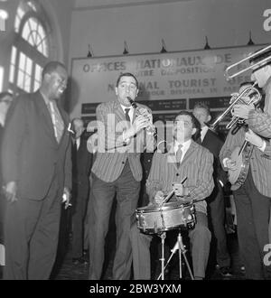 Louis Armstrong in Paris . Der König des Jazz, der zelebrierte Louis Armstrong und sein Orchester sind heute Morgen aus Abidjan in Paris angekommen, auf dem letzten Schritt seiner Reise aus Afrika. Louis Armstrong ist in Paris zu erscheinen in "Paris Blues" neben Paul Newman, Joanne Woodward und Sydney Poitier, unter der Leitung von Martin Ritt. Nach ihrer Ankunft aus Orly sind hier Louis Armstrong und Velma Middleton von den Musikern der Mowgli Jospin High Society Jazz Band umgeben, die auf dem Flughafen Paris spielen kamen. Dezember 1936 Stockfoto