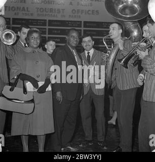 Louis Armstrong in Paris . Der König des Jazz, der zelebrierte Louis Armstrong und sein Orchester sind heute Morgen aus Abidjan in Paris angekommen, auf dem letzten Schritt seiner Reise aus Afrika. Louis Armstrong ist in Paris zu erscheinen in "Paris Blues" neben Paul Newman, Joanne Woodward und Sydney Poitier, unter der Leitung von Martin Ritt. Nach ihrer Ankunft aus Orly sind hier Louis Armstrong und Velma Middleton von den Musikern der Mowgli Jospin High Society Jazz Band umgeben, die auf dem Flughafen Paris spielen kamen. Dezember 1936 Stockfoto