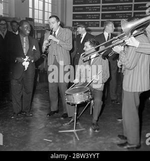 Louis Armstrong in Paris . Der König des Jazz, der zelebrierte Louis Armstrong und sein Orchester sind heute Morgen aus Abidjan in Paris angekommen, auf dem letzten Schritt seiner Reise aus Afrika. Louis Armstrong ist in Paris zu erscheinen in "Paris Blues" neben Paul Newman, Joanne Woodward und Sydney Poitier, unter der Leitung von Martin Ritt. Nach ihrer Ankunft aus Orly sind hier Louis Armstrong und Velma Middleton von den Musikern der Mowgli Jospin High Society Jazz Band umgeben, die auf dem Flughafen Paris spielen kamen. Dezember 1960 Stockfoto