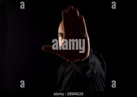 Dunkles Porträt eines Mannes mit Stoppschild auf schwarzem Background Stockfoto