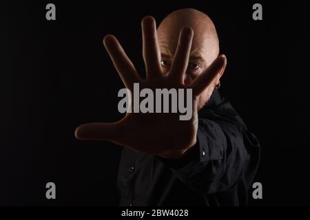 Dunkles Porträt eines Mannes mit offener Handfläche auf schwarzem Background Stockfoto