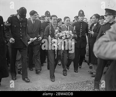 Japanische Flieger landen nach einem rekordverdächtigen 10,000-Meilen-Flug in Croydon. Nachdem die japanischen Piloten Masaaki Iinuma und Kenji Tsukakoshi alle Rekorde mit dem Flug von 10,000 Meilen von Tokio nach London in gut 100 Stunden zerschlagen hatten, landeten sie Croydon in ihrem Flugzeug Divine Wind [Mitsubishi Ki-15 Karigane Aircraft, Name: Kamikaze, Registration J-BAAI]. Die Flyer haben Krönungsgrüße aus Japan mitgebracht. Foto zeigt: Masaaki Iinuma, der 27-jährige Pilot, wird nach der Landung in Croydon von der Polizei zum Flugplatz-Hotel begleitet. April 1937 Stockfoto