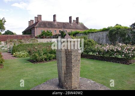 Alte Sonnenuhr auf einem Backsteinsockel, vor einem englischen Landhaus. Stockfoto