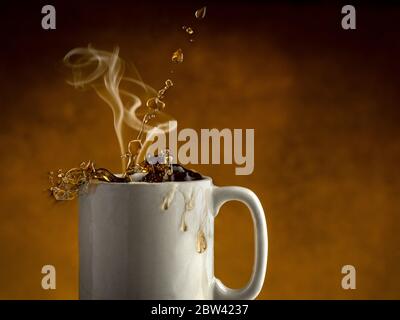 Dampf steigt aus einer Tasse Kaffee, während Kaffee aus der Kaffeetasse spritzt