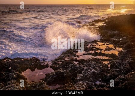 Große Wellen schlagen gegen Felsen bei Sonnenuntergang, Grand Cayman Blowholes Stockfoto