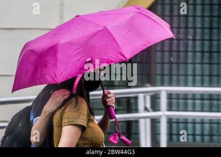 Manila, Philippinen. Mai 2020. Ein Paar, das Gesichtsmasken trägt, teilt sich während eines plötzlichen Regenguß in Manila, den Philippinen, 29. Mai 2020 einen Regenschirm. Quelle: Rouelle Umali/Xinhua/Alamy Live News Stockfoto