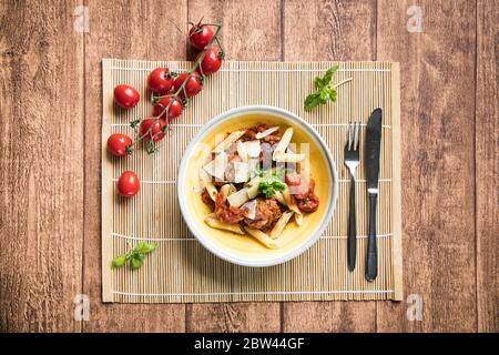 Penne mit Fleischbällchen in Tomatensauce und frischem Basilikum. Leichtes italienisches Abendessen im Sommer. Stockfoto