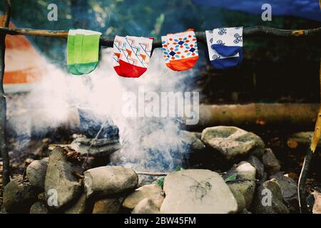 Trocknen nasser Socken am Lagerfeuer während des Campens. Socken trocknen auf Feuer. Aktive Erholung im Wald. Stockfoto