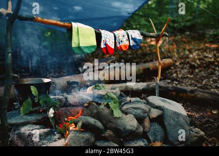 Trocknen nasser Socken am Lagerfeuer während des Campens. Socken trocknen auf Feuer. Aktive Erholung im Wald. Stockfoto