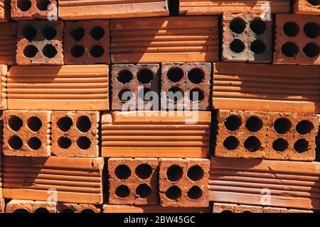 Hohle rote Ziegel in einem Stapel gestapelt, bereit für den Einsatz im Bau oder zum Verkauf. Baumaterial. Ordentlich gefaltet Ziegel, Foto für die Werbung. Kopieren Stockfoto