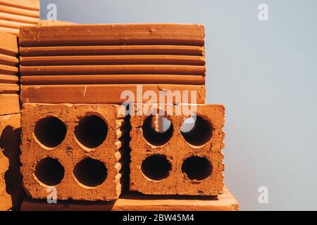 Hohle rote Ziegel in einem Stapel gestapelt, bereit für den Einsatz im Bau oder zum Verkauf. Baumaterial. Ordentlich gefaltet Ziegel, Foto für die Werbung. Kopieren Stockfoto