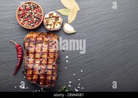 Holzkohle gegrilltes Steak mit Gewürzen, auf einem schwarzen Hintergrund. Grill Streifen auf Steak sichtbar Stockfoto