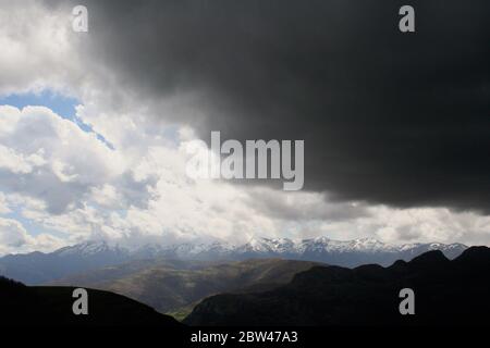 Schwere dunkle Wolken und schneebedeckte Berggipfel Picos de Europa Cantabria Spanien April 2010 Stockfoto