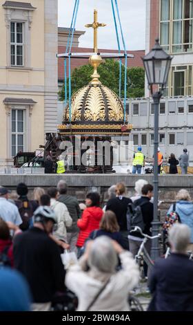 29. Mai 2020, Berlin: Zahlreiche Zuschauer beobachten beim Neubau des Berliner Schlosses, dem Humboldt Forum, wie die Kuppel mit dem Kreuz auf einem Sockel mit Engelsfiguren steht. Das ursprünglich ungeplante christliche Symbol auf dem Wiederaufbau des Palastes ist umstritten. Die erste Teileröffnung des Humboldt Forums, die für September geplant ist, wurde aus corona-Gründen verschoben. Das 644 Millionen Euro teure Gebäude soll jedoch noch in diesem Jahr eröffnet werden. Foto: Bernd von Jutrczenka/dpa Stockfoto