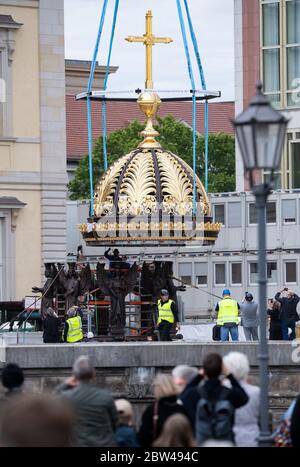 29. Mai 2020, Berlin: Zahlreiche Zuschauer beobachten beim Neubau des Berliner Schlosses, dem Humboldt Forum, wie die Kuppel mit dem Kreuz auf einem Sockel mit Engelsfiguren steht. Das ursprünglich ungeplante christliche Symbol auf dem Wiederaufbau des Palastes ist umstritten. Die erste Teileröffnung des Humboldt Forums, die für September geplant ist, wurde aus corona-Gründen verschoben. Das 644 Millionen Euro teure Gebäude soll jedoch noch in diesem Jahr eröffnet werden. Foto: Bernd von Jutrczenka/dpa Stockfoto