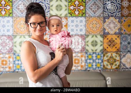 Porträt eines 6 Monate alten Mädchen mit jungen Mutter hält sie Stockfoto