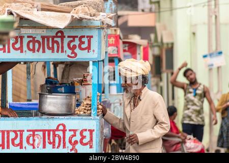 Somnath, Gujarat, Indien - Dezember 2018: Ein älterer Inder, der einen Turban trägt, kauft Tee von einem Straßenstand in der Altstadt. Stockfoto