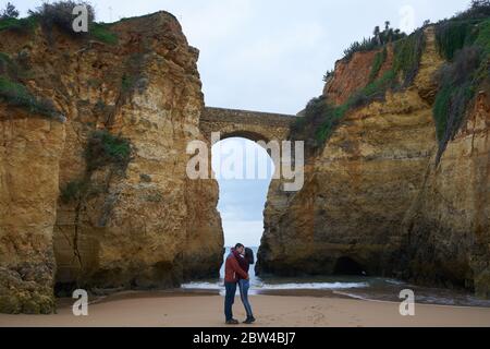 Pärchen küssen in Praia dos estudantes Strand mit Bogenbrücke in Lagos, Portugal Stockfoto
