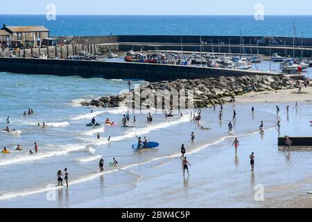 Lyme Regis, Dorset, Großbritannien. Mai 2020. Wetter in Großbritannien. Der Strand im Badeort Lyme Regis in Dorset ist voll mit Familien und Sonnenanbetern, die im Meer paddeln, um sich in der heißen Sonne am Nachmittag abzukühlen. Bild: Graham Hunt/Alamy Live News Stockfoto