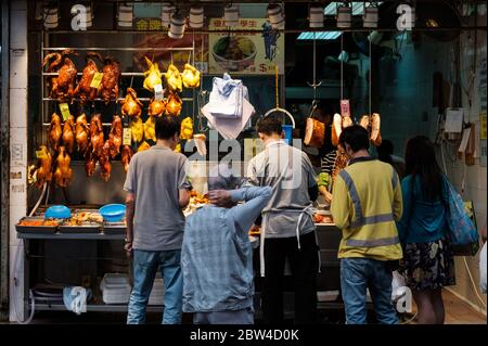 Hongkong - November 2019: Menschen kaufen auf dem Straßenmarkt in Hongkong geröstete Enten, peking-Ente und gebratene Gans Stockfoto