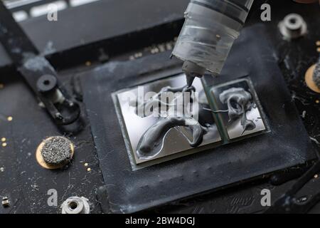 A Auftragen des Wärmeleitpaste auf den gpu-Chip für ein besseres Wärmemanagement, Makroansicht Stockfoto