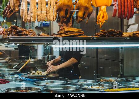 Hongkong - November 2019: Chinesischer Restaurantchef bereitet hinter dem Schaufenster Speisen zu Stockfoto