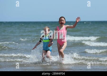 Der vierjährige Cian Walshe und seine Schwester Ella, acht, spielen im Meer vor Portmarnock Beach, Dublin, während das warme Wetter andauert. Bilddatum: Freitag, 29. Mai 2020. Das trockene, sonnige Wetter wird sich über das Juni-Feiertagswochenende fortsetzen, wobei die Temperaturen in einigen Gebieten auf 25 Grad Celsius steigen werden. Siehe PA Geschichte WETTER Sonne Irland. Das Foto sollte lauten: Brian Lawless/PA Wire Stockfoto