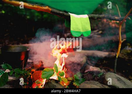 Trocknen nasser Socken am Lagerfeuer während des Campens. Socken trocknen auf Feuer. Aktive Erholung im Wald. Abenteuer Stockfoto