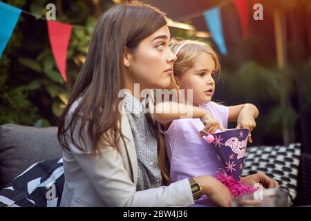 Lächelnde Mutter und Mädchen ihres Kindes feiern Kindergeburtstag Stockfoto