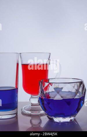 Zusammensetzung von verschiedenen Glasgläsern auf weißem Hintergrund mit bunten Flüssigkeiten Stockfoto