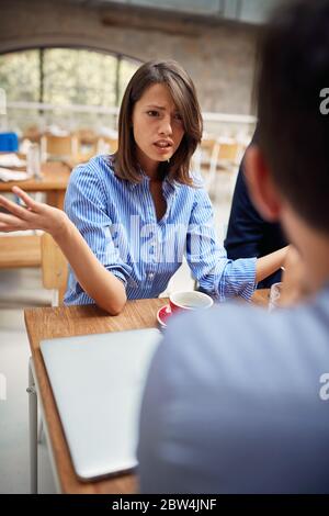 Frustrierte Geschäftsfrau, die im Büro mit einem Kollegen argumentiert Stockfoto