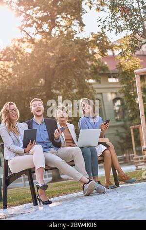 Eine Gruppe von Kollegen trifft sich an einem sonnigen Tag in einem Park Stockfoto