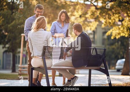 Eine Gruppe von Kollegen trifft sich an einem sonnigen Tag in einem Park Stockfoto